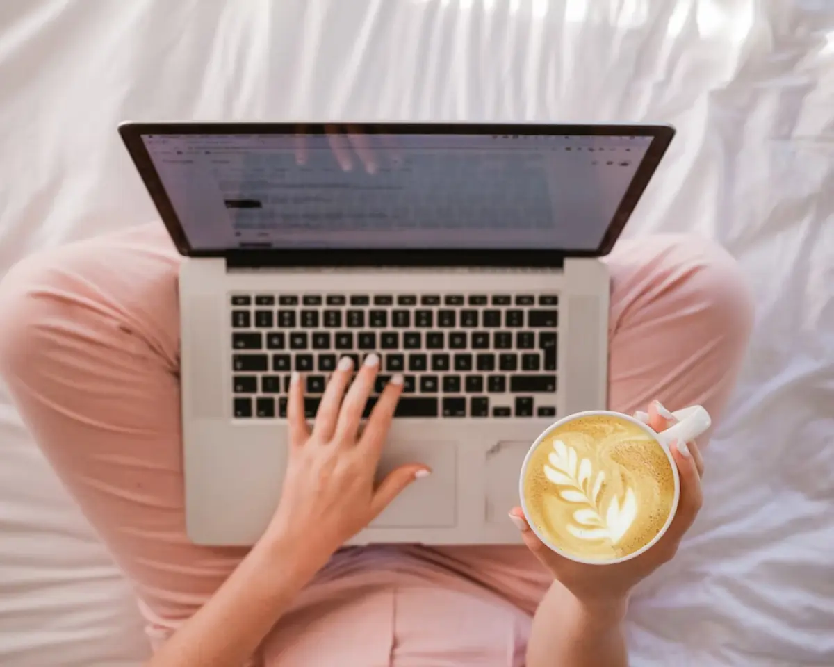 Someone cross-legged with a laptop and a latte